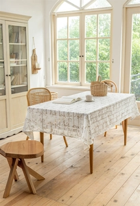 Detailansicht der cremefarbenen Jacquard-Tischdecke mit braunen Schnörkeln und Fransen