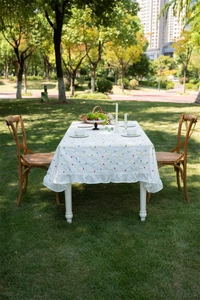 Detail of white cotton tablecloth with geometric prints and ruffled hem in outdoor setting