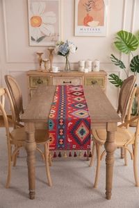 Close-up of Bohemian geometric pattern and red-brown tassels on woven table runner