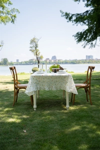 Detail of white cotton tablecloth featuring colorful geometric patterns and ruffle edges