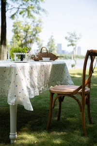 Detail of French cotton tablecloth with geometric embroidery and ruffled hem outdoors