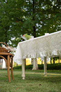Close-up of French lace cotton tablecloth with white leaf embroidery and ruffled edge