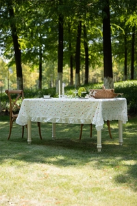 Detail of white cotton tablecloth with colorful geometric embroidery and ruffled hem