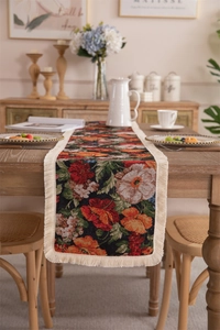 Detail of vintage jacquard table runner with floral patterns and white fringe tassels
