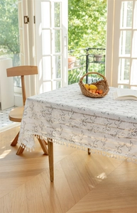 Detailansicht der weißen Tischdecke mit silbernem Blumenmuster und Fransenverzierung