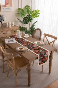 Close-up of floral jacquard table runner with vintage fringe details on wooden surface