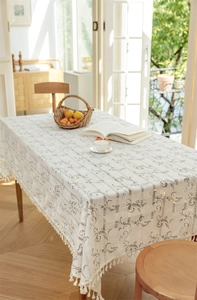 Detailansicht der cremefarbenen Tischdecke mit Fransen und floralen Mustern
