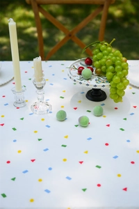 Outdoor picnic setup featuring white tablecloth with colorful geometric patterns
