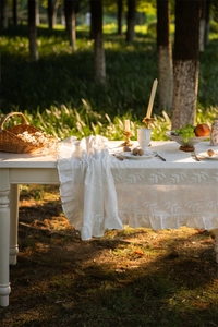 Close-up of French lace cotton tablecloth with white leaf embroidery and ruffled edges