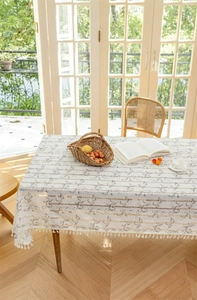 Nahaufnahme der weißen rechteckigen Tischdecke mit silbernen Blumenmustern und Quasten
