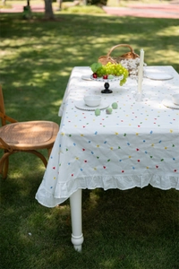 Detail of white cotton tablecloth featuring geometric embroidery and ruffled edges