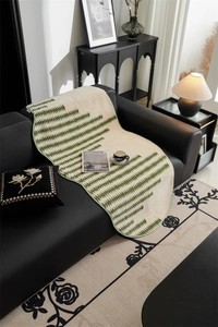 Detail of soft cream white sofa throw with green geometric jacquard and plush texture