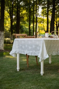 Detailed view of French lace tablecloth with floral embroidery and ruffle edges