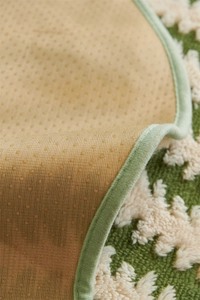 Close-up of green and white jacquard sofa cushion with non-slip backing and stitched edges