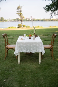 Detail of white French lace tablecloth with floral embroidery and ruffle edge outdoors