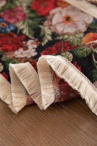 Macro shot of vintage floral jacquard table runner with delicate cream fringe tassels