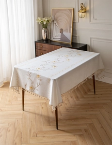 Detail of embroidered coffee leaf pattern and beige tassel edges on rectangular tablecloth