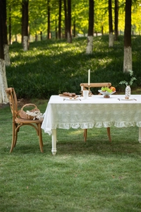 Close-up of French white lace tablecloth featuring floral embroidery and ruffled edges