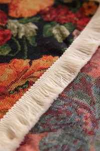 Detailed close-up of retro floral jacquard table runner with dense white tassel trim