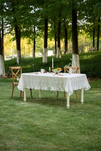 Close-up of white French lace tablecloth with embroidered flowers and ruffle edges