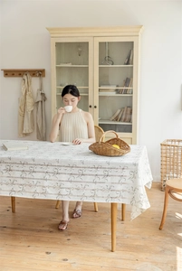Detailansicht der cremefarbenen Tischdecke mit grauen Schnörkelmustern und Fransenquasten