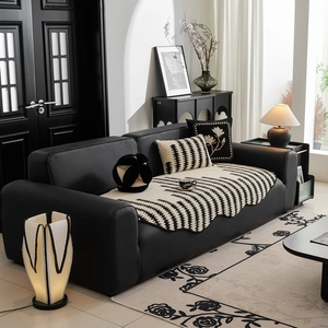 Modern black and white striped jacquard sofa cover with matching pillows on leather couch