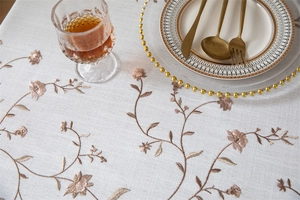 Close-up of white tablecloth with coffee leaf embroidery and natural linen texture