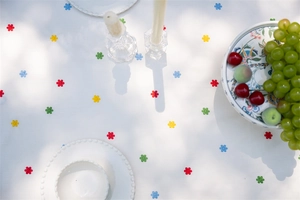 Detail of white cotton tablecloth featuring colorful floral embroidery and ruffled edge decor