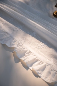 Close-up of white floral embroidery and ruffled edges on French style lace cotton tablecloth