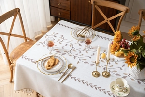Detail of embroidered vine leaf tablecloth with elegant fringe tassels in a dining room
