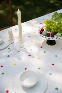 Detail of French cotton tablecloth with colorful floral pattern and ruffled edge on garden table