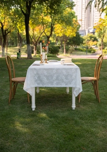 Detailed view of white cotton lace tablecloth with leaf embroidery and scalloped edges
