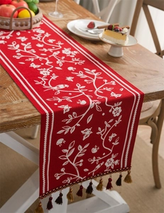 Detail of red table runner with white floral bird pattern and colorful fringe tassels