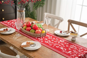Detail of red floral bird pattern table runner on wooden dining table setup