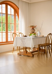 Detailed view of beige cotton linen tablecloth with brown leaf prints and fringe trim