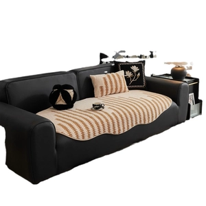 Modern jacquard sofa mat with zigzag patterns and floral embroidered pillows on a leather sofa