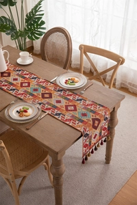 Close-up of bohemian woven table runner with geometric patterns and fringe tassels