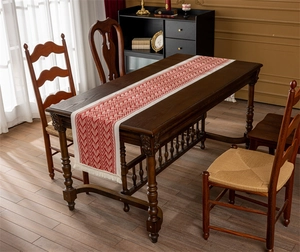 Close-up of red and beige V-shaped jacquard knit table runner with thick fringe edge