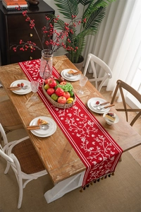 Macro detail of red festive table runner with floral patterns and luxury golden tassels