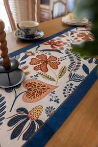 Close-up of vintage floral jacquard table runner with blue borders and intricate gold accents
