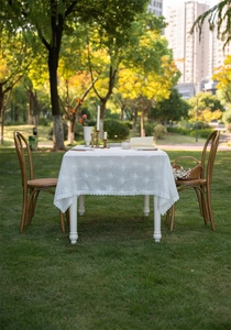 Detail of white lace tablecloth with floral embroidery and scalloped edges for picnic decor