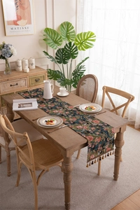 Macro detail of vintage floral table runner with elegant tassels on a wooden dining table