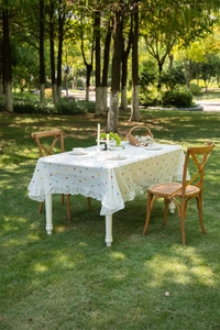 Detail of white cotton tablecloth with floral embroidery and ruffled hem in sunlight