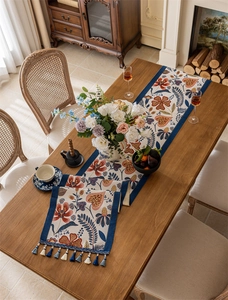 Close-up of jacquard table runner featuring red floral patterns and blue tassel fringe