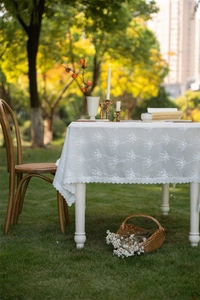 Detail of white French lace tablecloth with floral embroidery and wavy scalloped edges