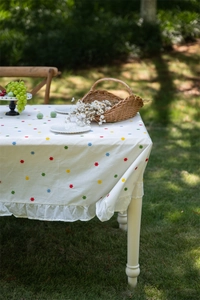 Detail of white cotton tablecloth featuring floral embroidery and elegant ruffled edges