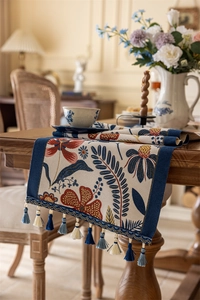 Detail of vintage floral jacquard table runner with fringe tassels and intricate patterns