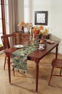 Close-up of olive green table runner with floral daisy patterns and tassel fringe detail