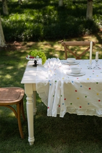 Macro detail of French floral embroidery and elegant ruffle edge on ivory cotton tablecloth