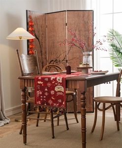 Detail of red festive table runner with traditional Chinese jacquard and dark tassels
